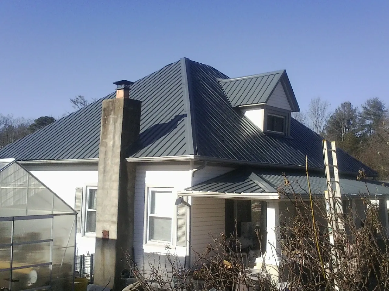 Dark blue standing seam metal roof on a white farmhouse with dormer — Slate & Tile Roof Repair by Roofing Brothers in Melville