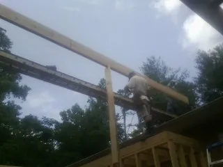 Carpenter setting a ridge beam over a new addition frame — Ice Dam Removal by Roofing Brothers in Melville
