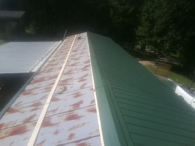 Old rusted panels beside newly installed green metal roofing — Wind Damage Roof Repair by Roofing Brothers in Melville