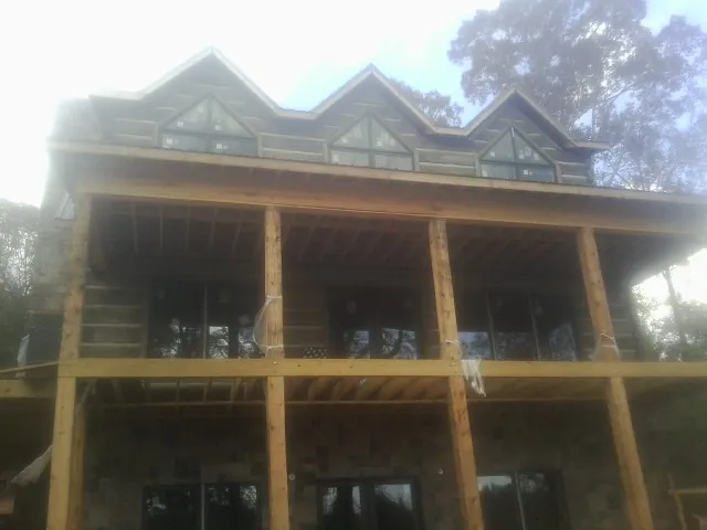 Dormers and porch framing on a large log home under construction — Roof Coating work by our crew in Melville