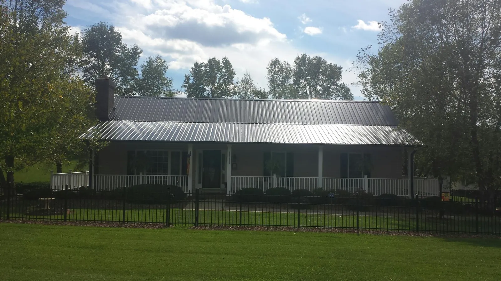 Gray metal roof on a brick ranch with a full width front porch — Gutter Guard Installation work by our crew in Melville