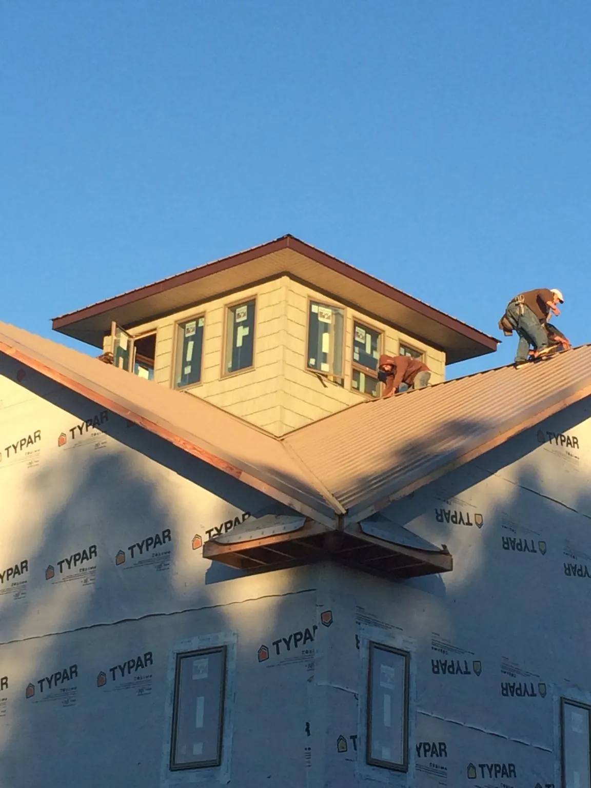 Roofers working around a rooftop cupola on a new metal roof at sunset — Roof Waterproofing in Melville by Roofing Brothers